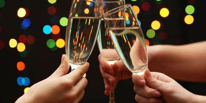 woman-hand-with-glasses-of-champagne-on-garland-background