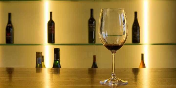 wine-glass-against-array-of-bottles