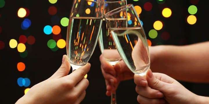 woman-hand-with-glasses-of-champagne-on-garland-background
