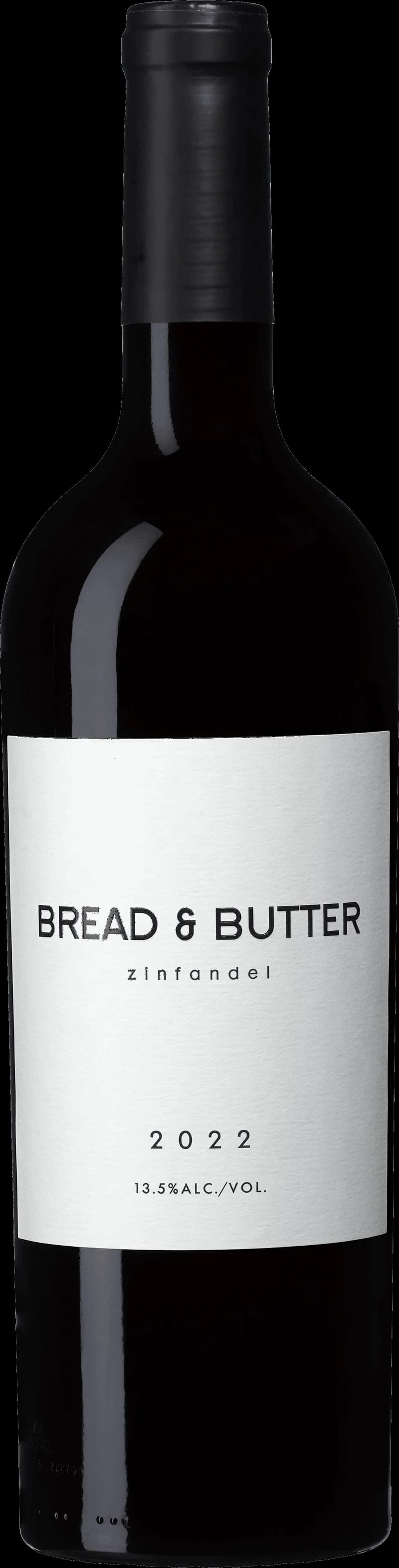 Ett glas rött vin bredvid en bit bröd med smör på en träbänk.