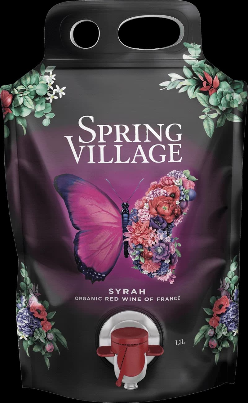 En flaska rött vin på ett bord i en vårby med blommande träd.