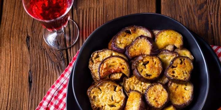 Medelhavet: krispiga aubergineskivor på tallrik och ett glas rött vin