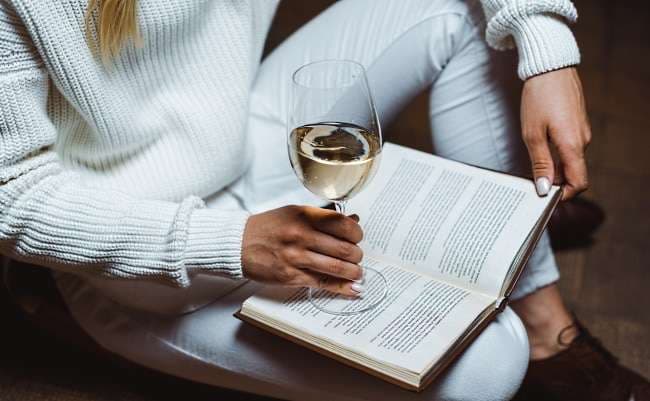 böcker om vin - en kvinna som läser med ett glas vin