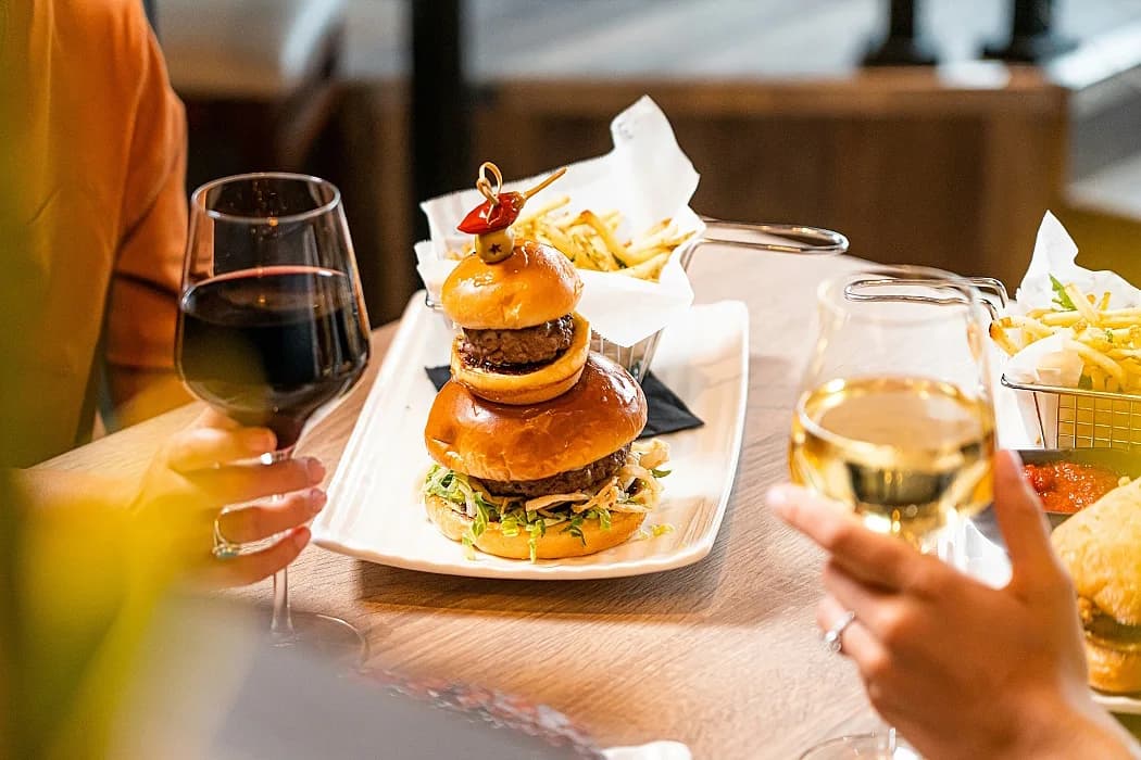 Omslagsbild på grillad hamburgare med ett glas rött vin.