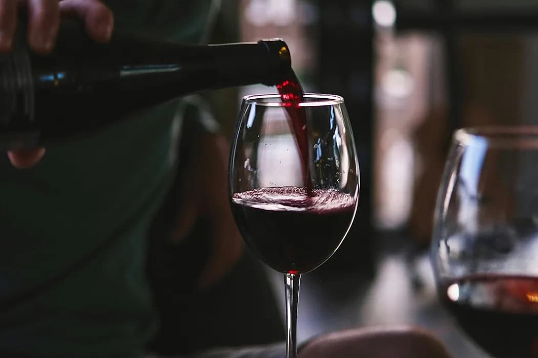 Omslagsbild till reportaget Vinets magi med vinflaskor och glas i varm belysning