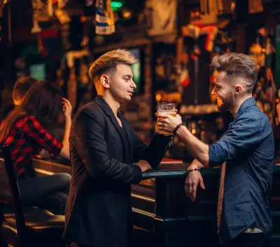 2 glada killar i en pub som dricker öl