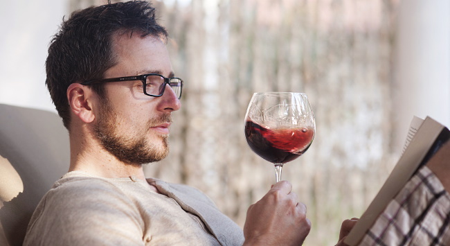 vinböcker - kille som dricker rödvin och läser bok