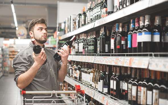betygsätter vin - en kille som står ch välker i butiken